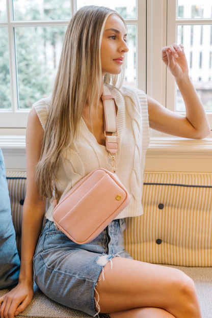 Woman wearing a pink Modern+Chic Willow Vegan Leather Convertible Crossbody Bag in front of a window.