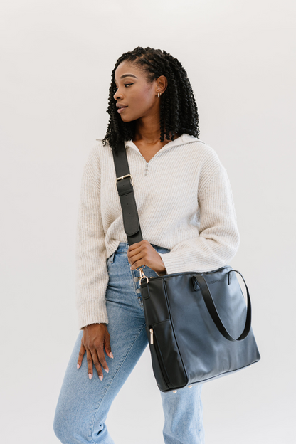 A woman wearing a black tote crossbody-style.