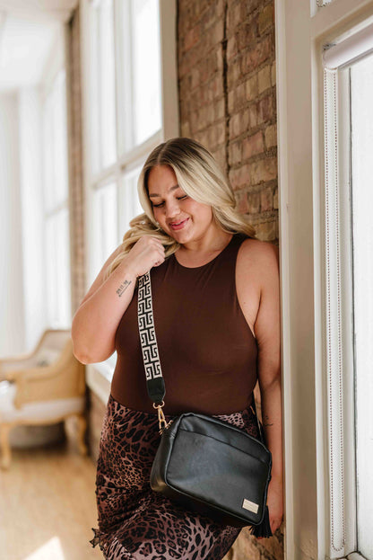 A blonde woman modeling a Modern+Chic Black Alice Crossbody Bag with abstract printed strap.