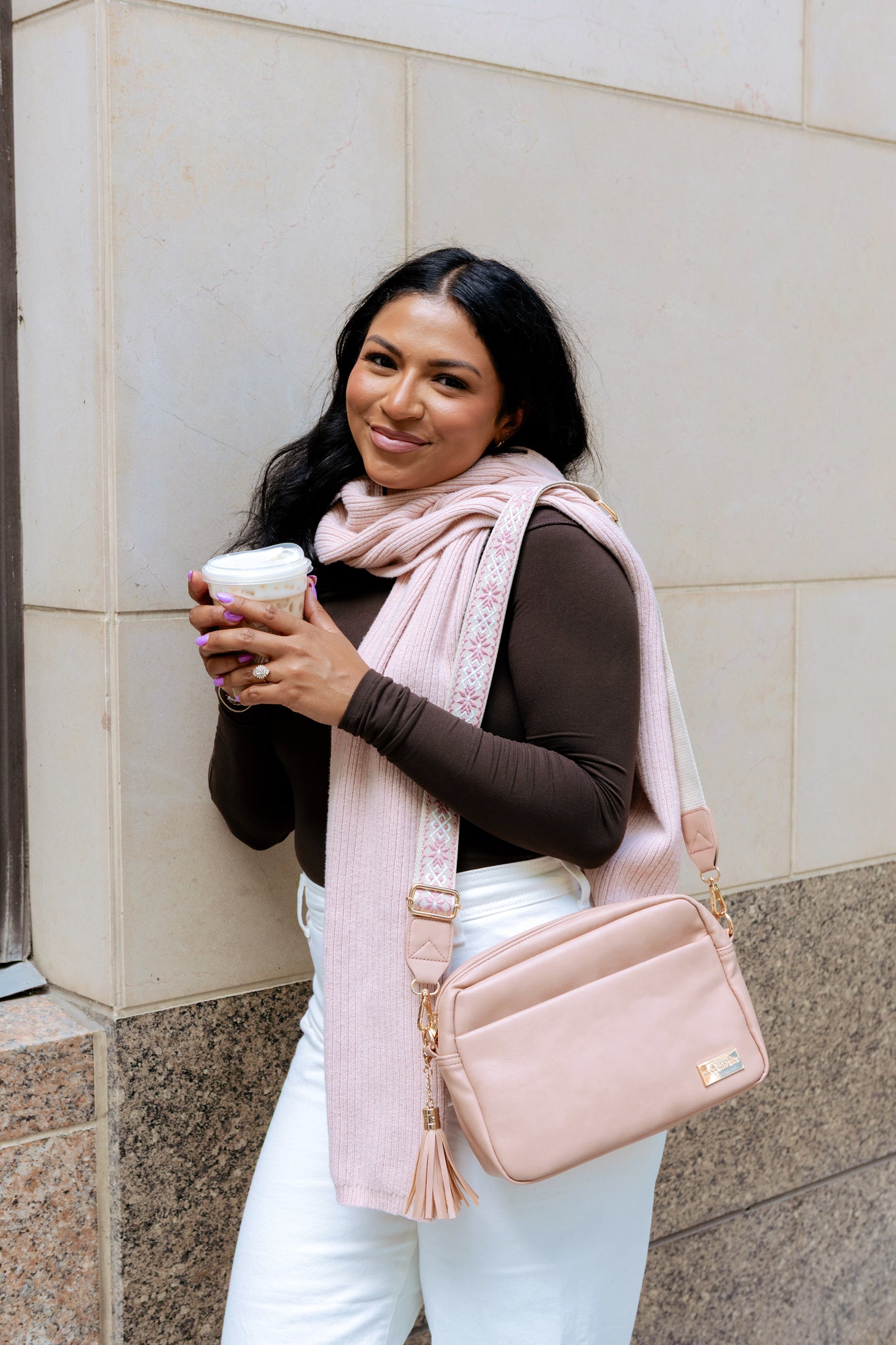 A olive skinned, dark haired woman modeling a dusty blush colored Modern + Chic Alice Crossbody bag. 