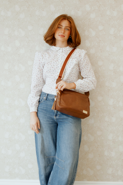 A red-haired woman modeling a Modern+Chic Coffee Alice Crossbody Bag: Vegan Leather Bag, Key Leash & Wallet