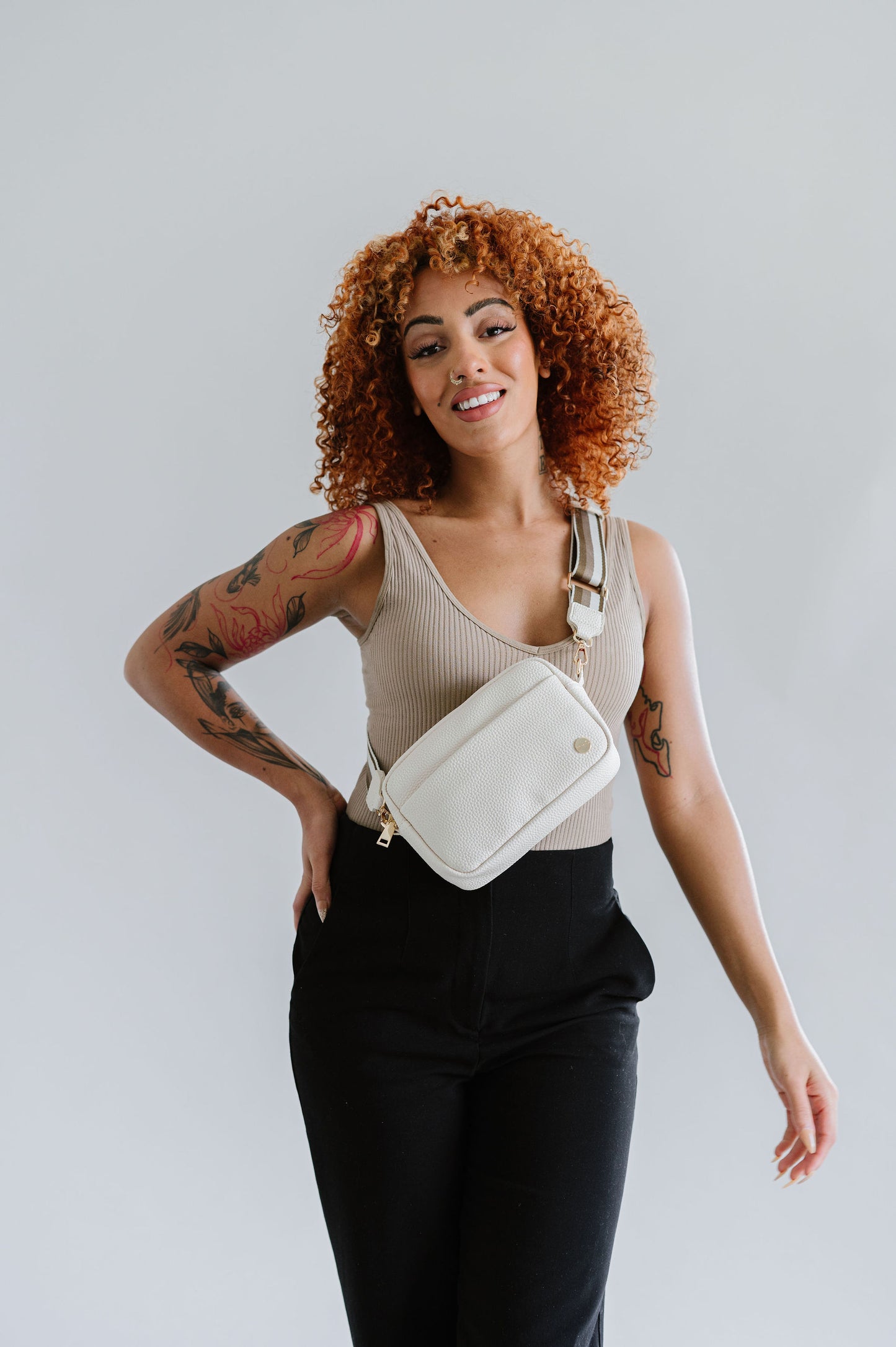 Woman wearing a cream Modern+Chic Willow Vegan Leather Convertible Crossbody Bag on a white background. 
