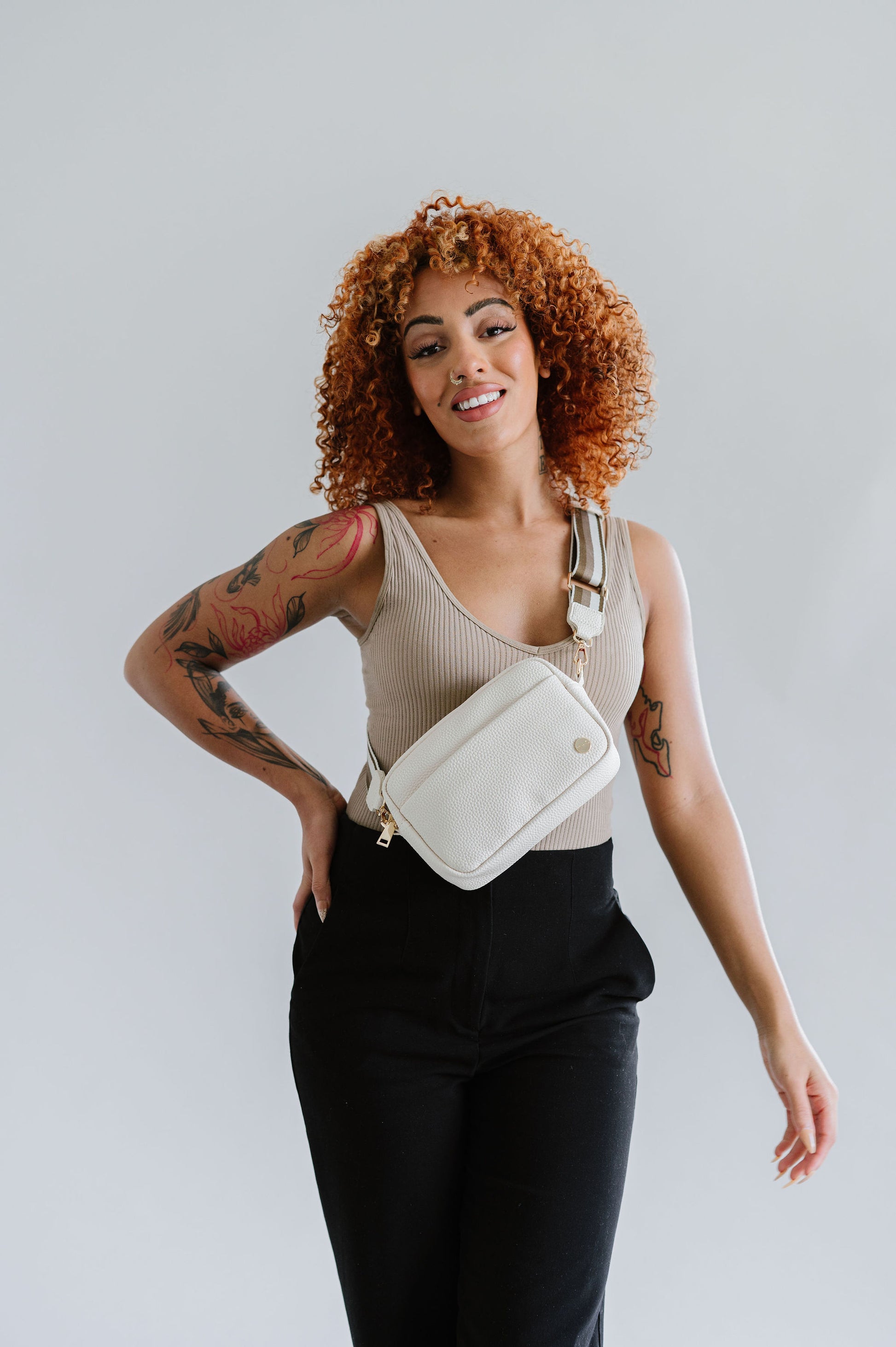 Woman wearing a cream Modern+Chic Willow Vegan Leather Convertible Crossbody Bag on a white background. 