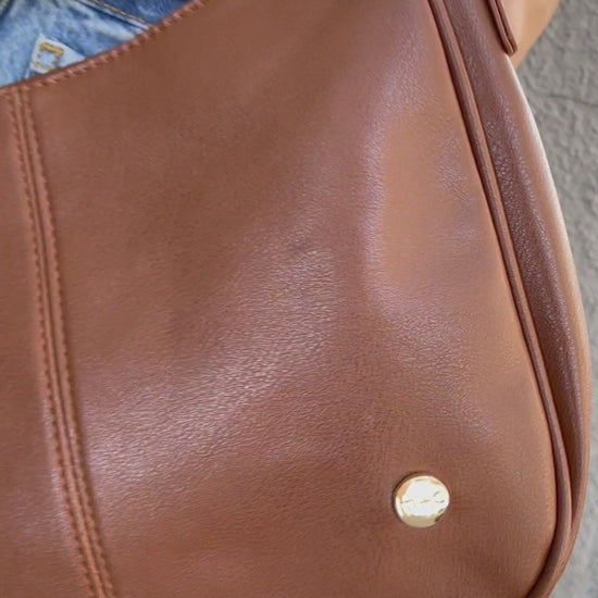 A video showing a mode posing with a variety of colors of a Modern + Chic Marissa vegan leather crossbody handbag.