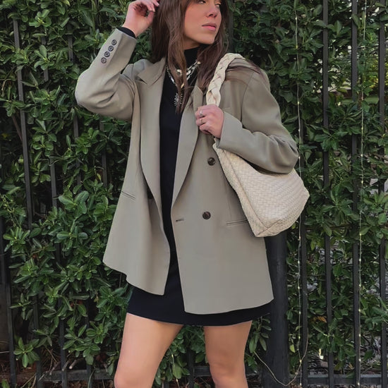A video of a woman modeling an ivory Modern+Chic Kelly Woven Convertible Crossbody Shoulder Bag with included vegan leather adjustable crossbody strap outdoors.