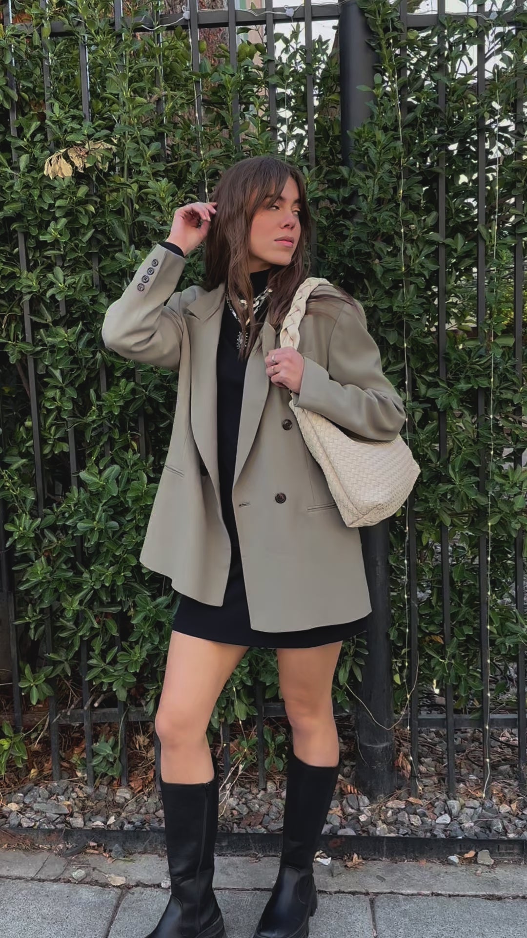 A video of a woman modeling an ivory Modern+Chic Kelly Woven Convertible Crossbody Shoulder Bag with included vegan leather adjustable crossbody strap outdoors.