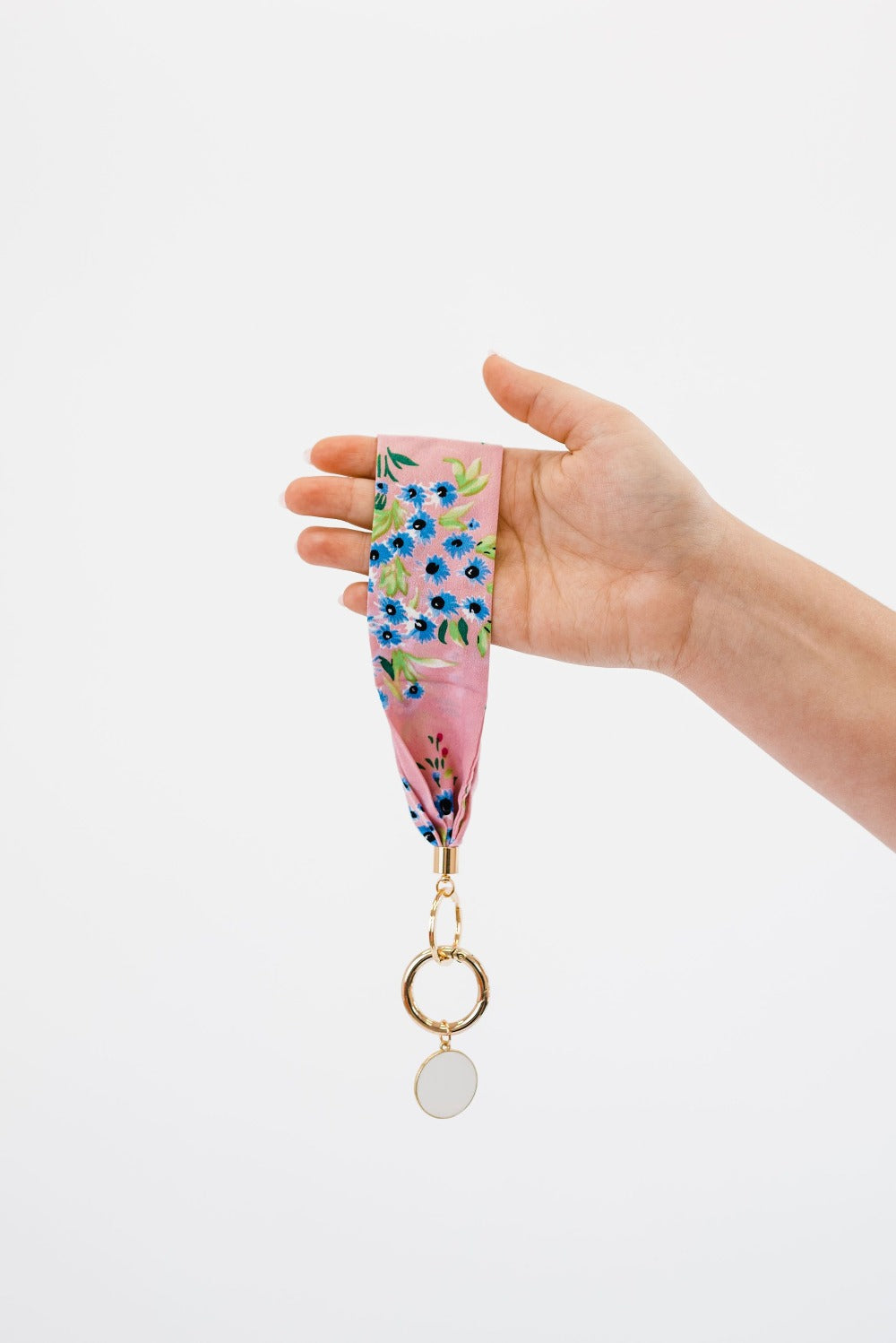A hand holding Modern + Chic Luna Fabric Keychain Bracelet for Women in front of a white background.