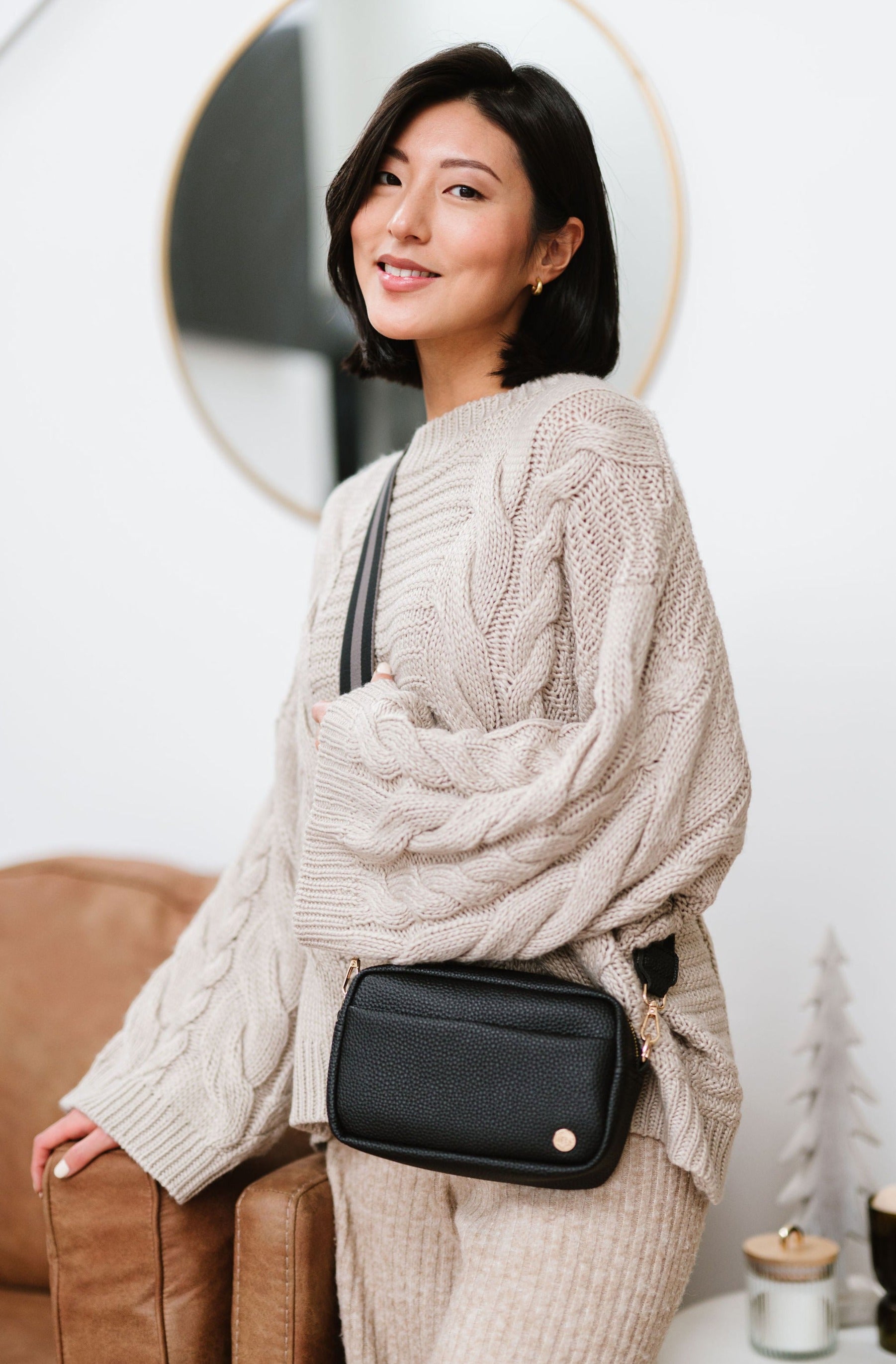 Woman wearing a black Modern+Chic Willow Vegan Leather Convertible Crossbody Bag in a living room.