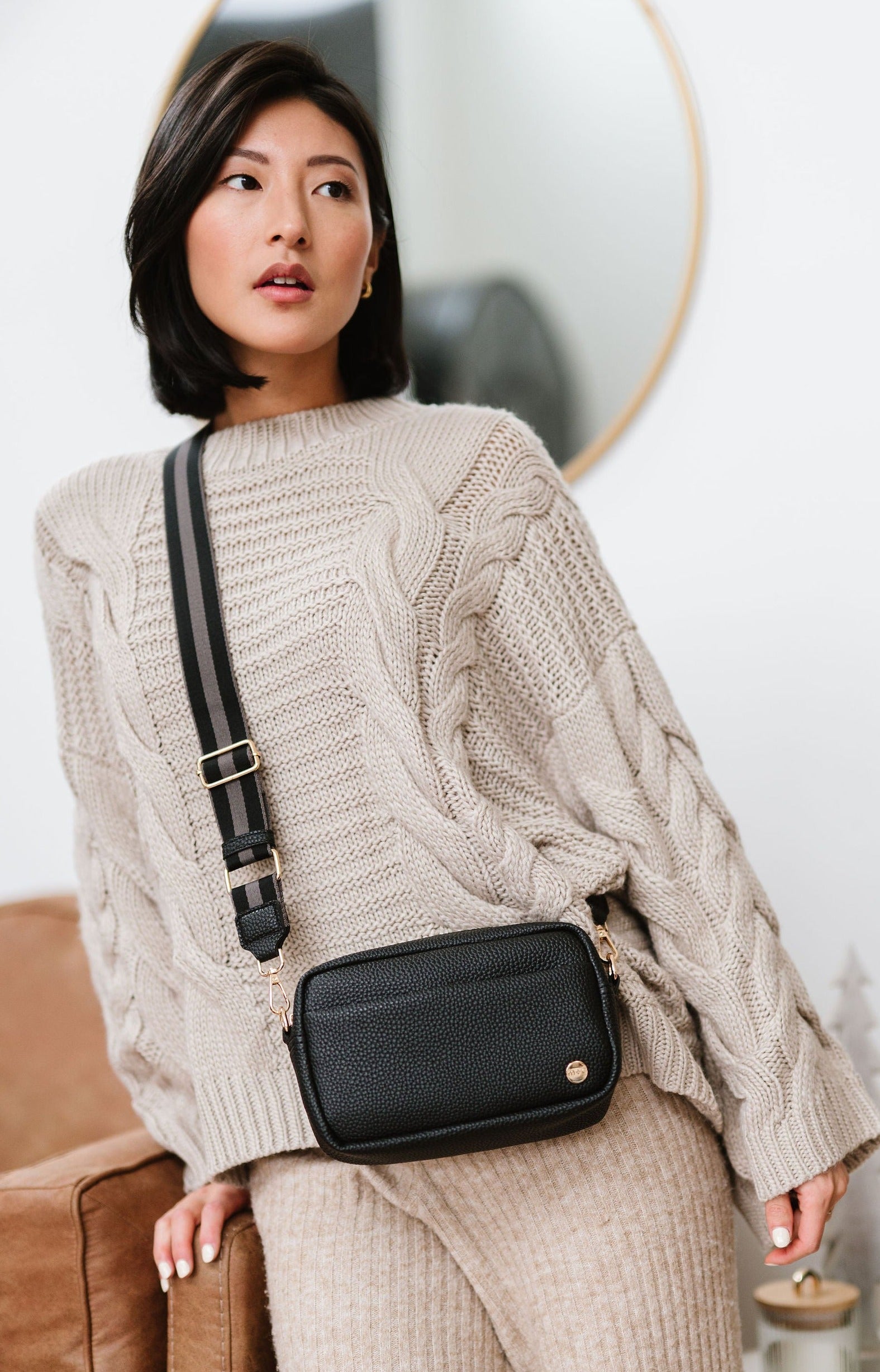 Woman wearing a black Modern+Chic Willow Vegan Leather Convertible Crossbody Bag on a white background. 