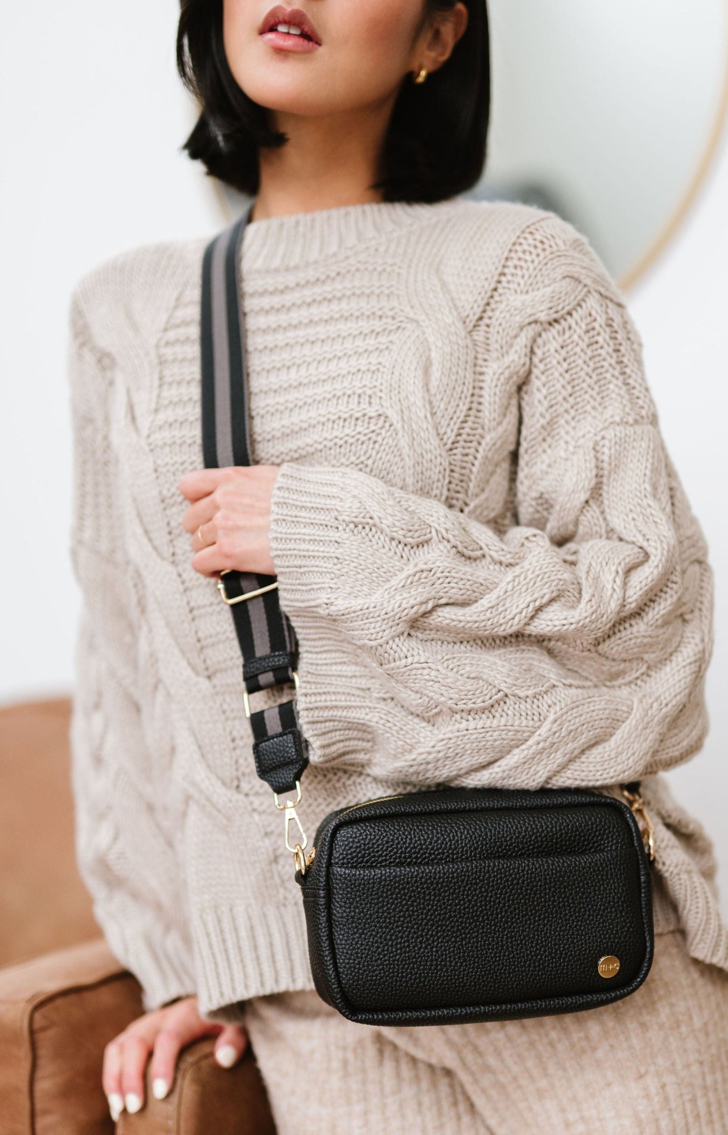 Woman wearing a black Modern+Chic Willow Vegan Leather Convertible Crossbody Bag on a white background. 